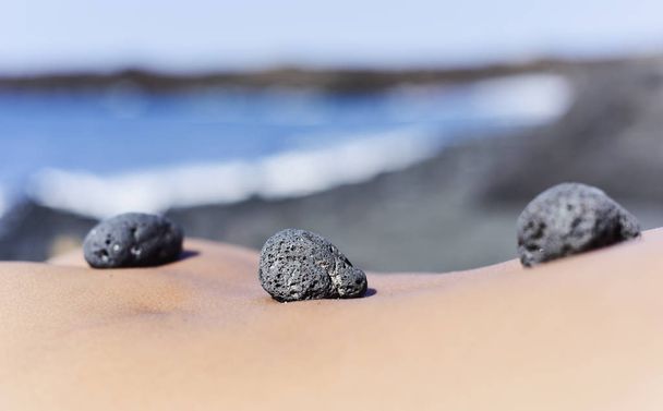 pedras na parte de trás de um homem na praia
 - Foto, Imagem