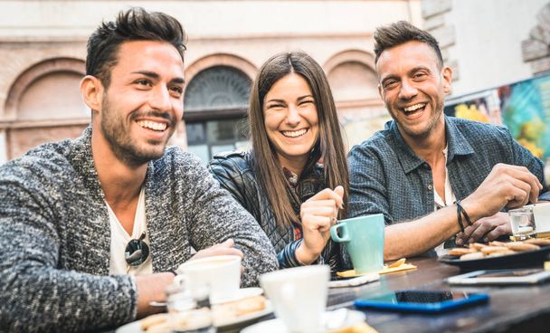 Happy vrienden praten en plezier in café restaurant drinken cappuccino en warme thee - jongeren samen op mode cafetaria - concept van de vriendschap met vrouwen en mannen in de koffiebar - koud filter - Foto, afbeelding