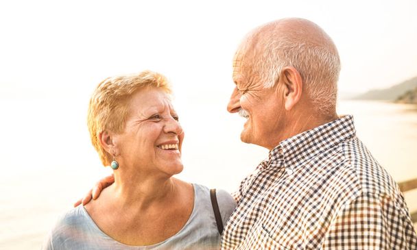 glückliches Rentnerehepaar, das sich im Urlaub im Freien amüsiert - Liebeskonzept des fröhlichen Älterwerdens und des Lebensstils im Ruhestand mit einem Mann, der Frau in die Augen schaut - warme helle Filterfarbtöne - Foto, Bild