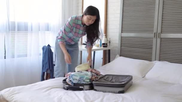 Asian girl pulled out the clothing in the suitcase and threw them all over around the bedroom. - Felvétel, videó