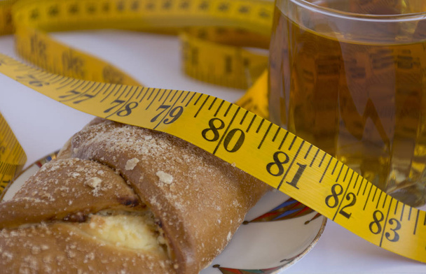 measuring tape lies on a bun next to a Cup of tea - Foto, afbeelding