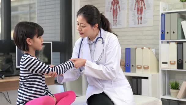 beautiful doctor checks up the good condition of kids injured arm. doctor and patient celebrate the hurt elbow recovery perfect hand high five together. - Footage, Video