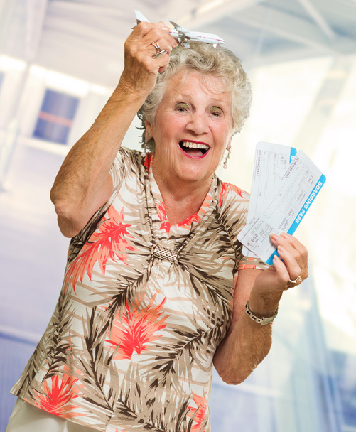 Mujer mayor sosteniendo tarjeta de embarque y miniatura
 - Foto, imagen
