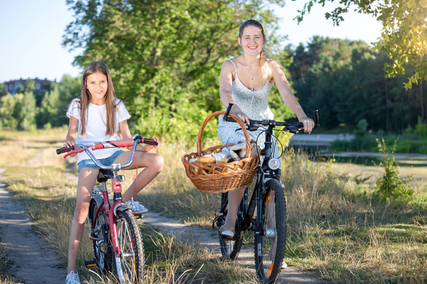 公園で 10 代の娘と幸せな若い母乗馬自転車 - 写真・画像