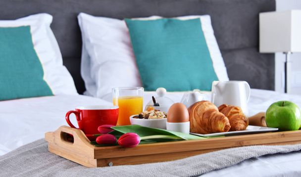 Ontbijt op dienblad op bed in hotelkamer - Foto, afbeelding