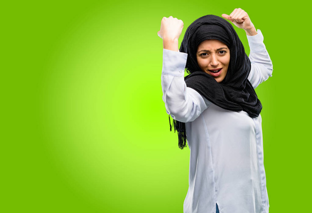 Jonge Arabische vrouw het dragen van hijab tonen biceps uiting van kracht en sportschool concept, gezond leven zijn goed - Foto, afbeelding