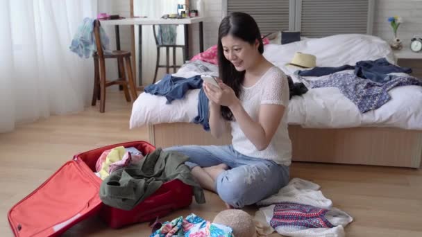 Woman tapping her cell phone in her messy unclean room. She is looking up her list and make sure she bring everything. - Metraje, vídeo