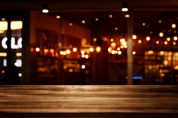 Image of wooden table in front of abstract blurred restaurant lights background. - Photo, Image