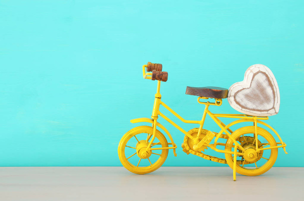Image of metal yellow bicycle with heart, present for dad. Father's day concept. - Foto, afbeelding