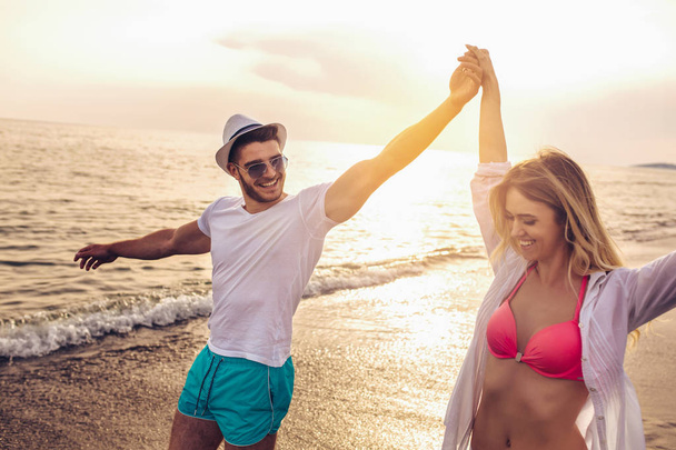glückliches Paar läuft bei Sonnenuntergang am Strand. - Foto, Bild