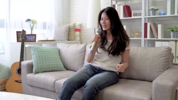 Asian woman singing exciting songs in the living room. She is celebrating the coming weekend. - Materiaali, video