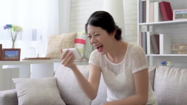 Asian woman burst into laughter and look at the camera while she is watching the funny films on the social media phone. - Materiaali, video