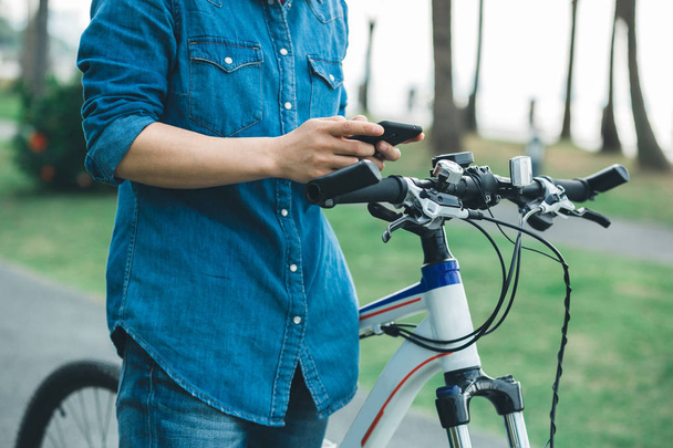 cyclist using cellphone while riding bike in tropical park - Fotó, kép