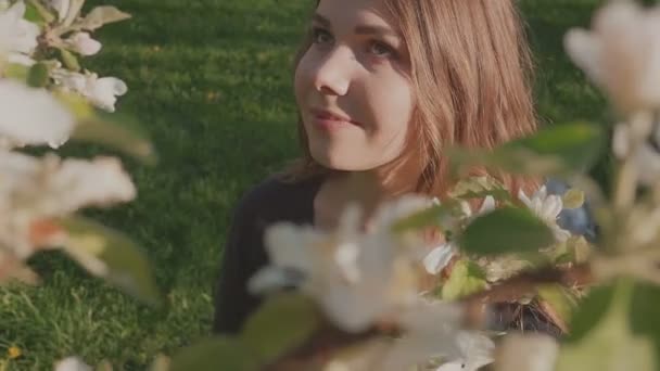 young happy woman walking in an apple orchard in the spring flowers white. Portrait of a beautiful girl - Footage, Video