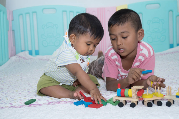 Dos hermanos juegan juguete de madera en la habitación
 - Foto, imagen