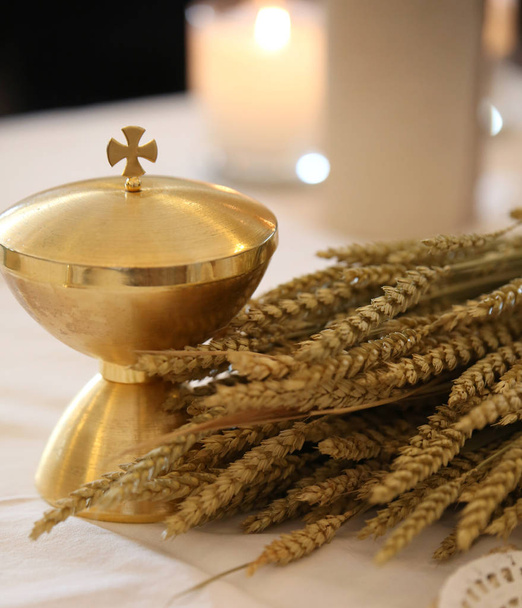 golden chalice on an altar in a church with ears of wheat - Photo, Image