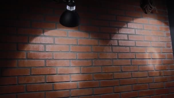 A lâmpada incandescente brilha em uma parede de tijolo, a textura de um tijolo
. - Filmagem, Vídeo