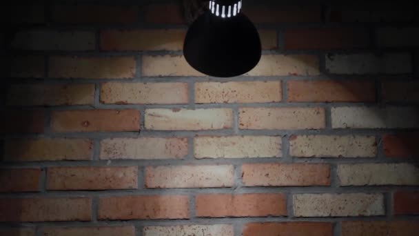De gloeilamp schijnt op een bakstenen muur, de textuur van een baksteen. - Video