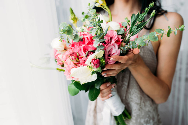 Bride in white wedding dress with a beautiful bouquet of roses - Photo, Image