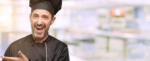 Kıdemli şef şapkalı bir şey lokanta mutfağı, boş elinde tutan adam, yemek - Fotoğraf, Görsel