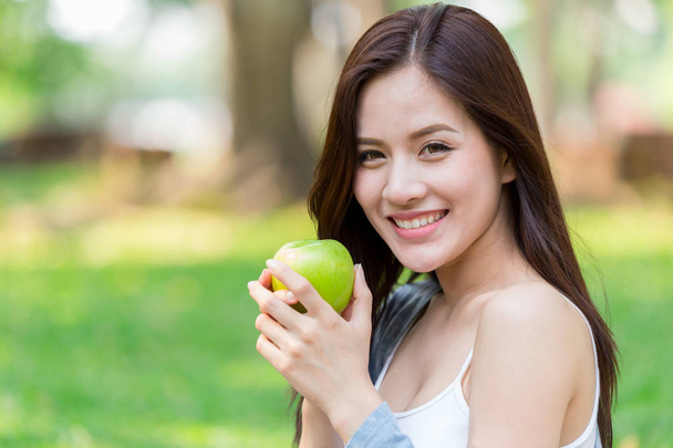 Belle asiatique femmes modèle main tenir pomme verte dans le parc en plein air saine alimentation bio fruits régime concept
 - Photo, image