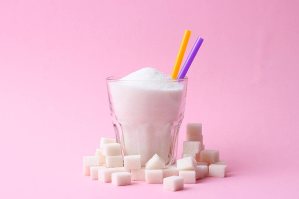 A transparent glass filled with sugar on a pastel background with space for text. cubes of sugar. minimalism, diabetes, calories, sweet drinks.  - Foto, afbeelding