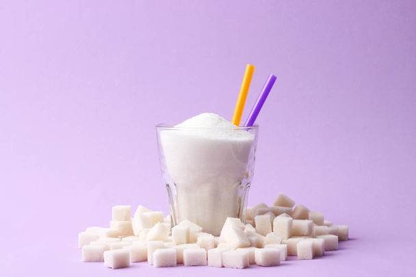 A transparent glass filled with sugar on a pastel background with space for text. cubes of sugar. minimalism, diabetes, calories, sweet drinks.  - Foto, immagini