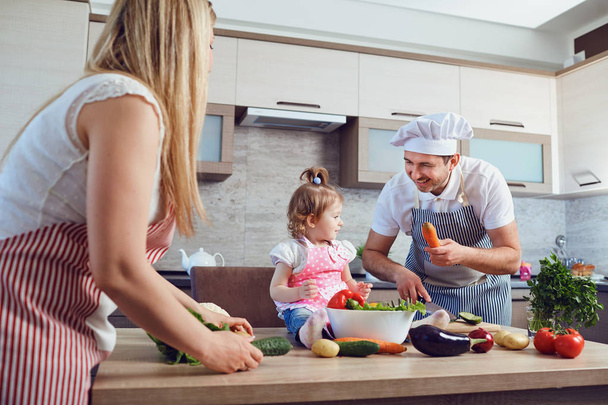 Eine glückliche Familie bereitet das Essen in der Küche zu. - Foto, Bild
