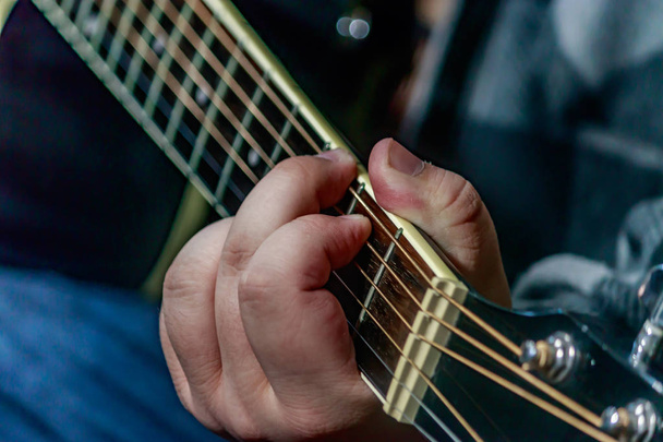 рука грає на чорній гітарі
 - Фото, зображення