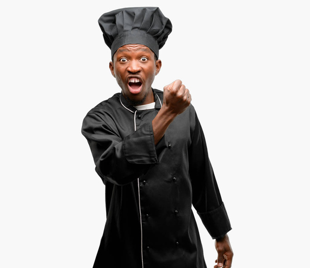 Joven cocinero negro con sombrero de chef irritado y enojado expresando emoción negativa, molesto con alguien
 - Foto, Imagen