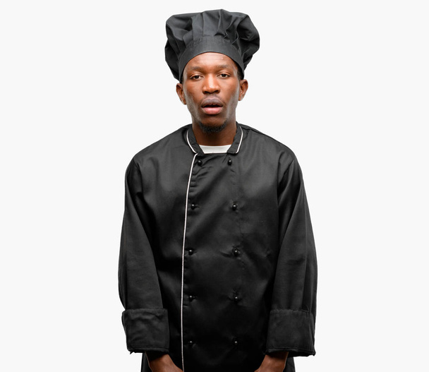 Joven cocinero negro con sombrero de chef con expresión somnolienta, sobrecargado de trabajo y cansado
 - Foto, Imagen