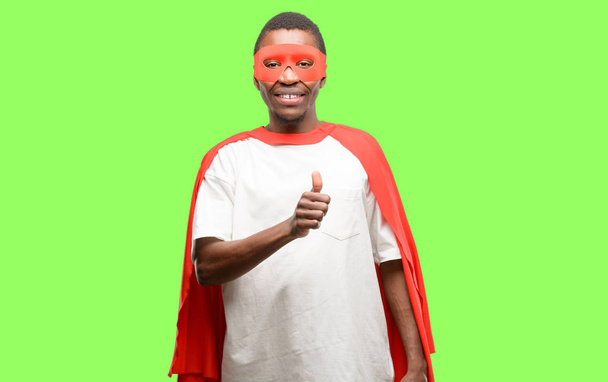 Afrikaanse zwarte superheld man die lacht in grote lijnen weergegeven: duimschroef opwaarts gebaar camera, expressie van en goedkeuring - Foto, afbeelding
