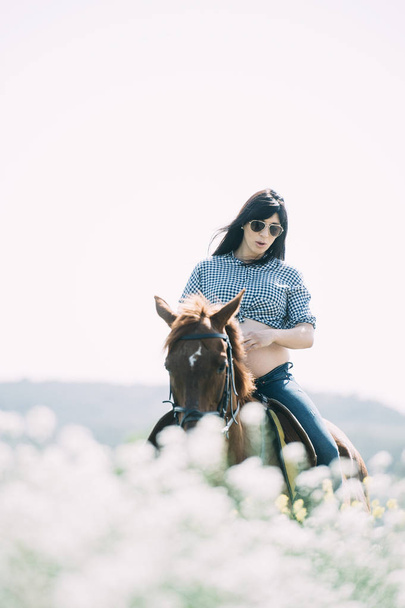 Raskaana oleva nainen hevosen kanssa vihreällä pellolla
 - Valokuva, kuva