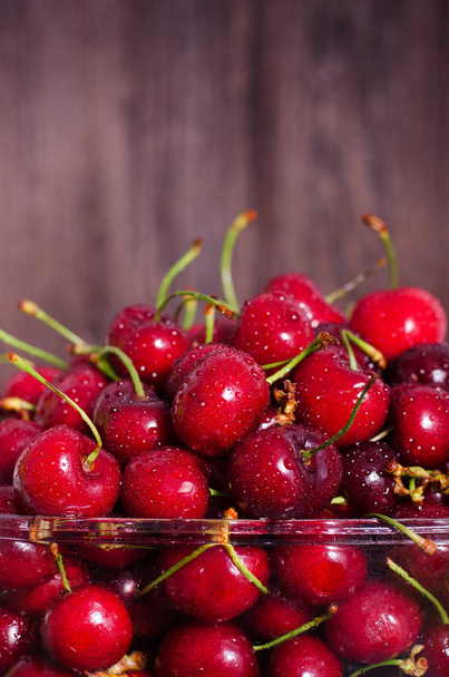 Sweet red cherries in glass bowl on dark wooden backgound with copy space. Summer and harvest concept. Vegan, vegetarian, raw food - Photo, image