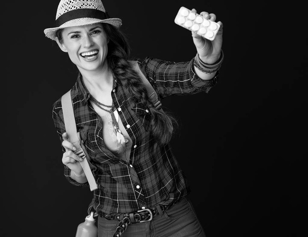 smiling active woman hiker with backpack showing tablets in a blister pack  - Zdjęcie, obraz
