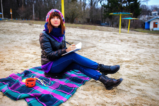 όμορφη κοπέλα καθόταν στην παραλία και έχει εγγραφές σε μια φορητών υπο - Φωτογραφία, εικόνα