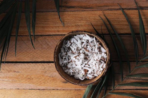 fresh natural coconut shavings, palm leaves, half coconut on the background of wood.  - Photo, Image