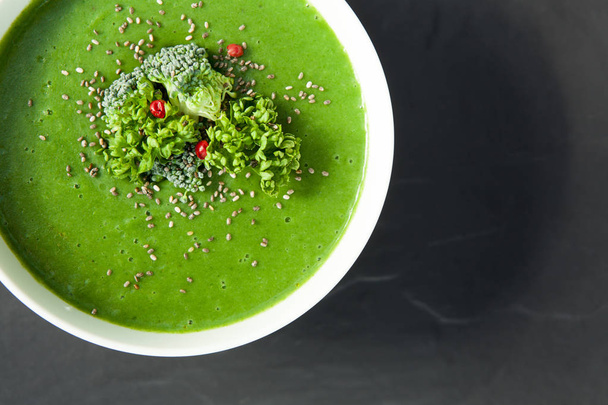 Grüne Spinatsuppe mit Brokkoli in weißer Schüssel isoliert auf dunkelgrauem Hintergrund von oben. Geeignet für Lebensmittelillustrationen, Diätartikel. - Foto, Bild