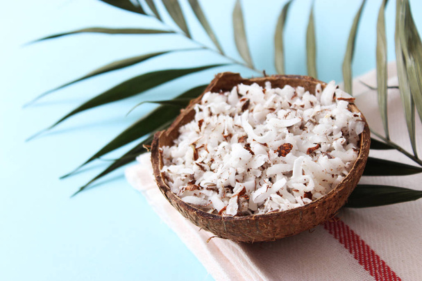 fresh coconut shavings and palm leaf on a colored background. - Photo, Image
