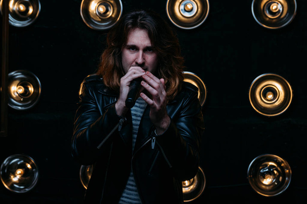 Brutal singer with long hair, with microphone on the stage - Foto, imagen