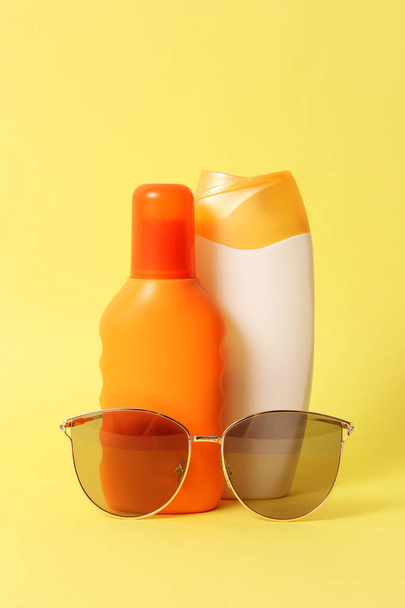several sunscreens and sunglasses on a colored background. Cosmetics for safe sunburn. - Φωτογραφία, εικόνα