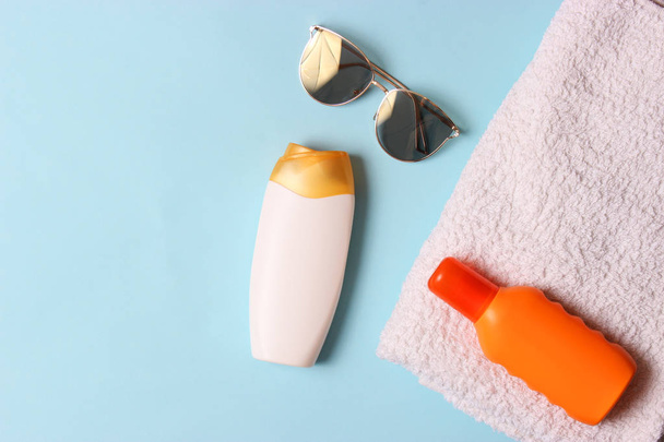 πετσέτα, καπέλο, αντηλιακό, γυαλιά σε έγχρωμο φόντο. Καλλυντικά για ασφαλή sunburn.top προβολή, flatlay  - Φωτογραφία, εικόνα