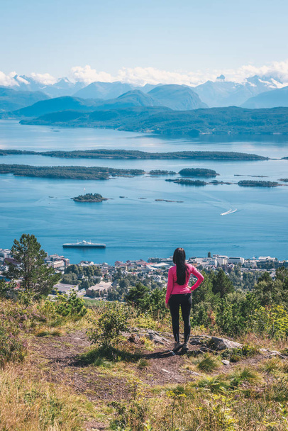 Jonge actieve vrouw genieten van spectaculaire Varden, Molde Panorama uitzicht over Noorse fjord, bergen, eilanden en klein stadje. Uitzicht vanaf de top van de rots. - Foto, afbeelding