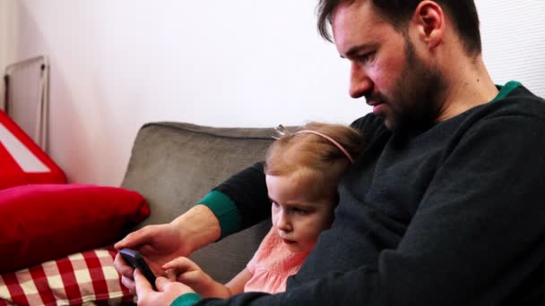 der Vater hält ein Smartphone in der Hand und die Tochter drückt auf den Bildschirm - Filmmaterial, Video