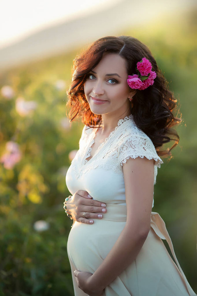 beautiful pregnant woman posing on green field in white dress - Photo, image