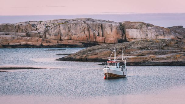 Barco solitario al atardecer en el mar tranquilo entre las rocas. Verdens Ende, extremo sur de la isla de Tjme en Vestfold, Noruega
. - Foto, Imagen