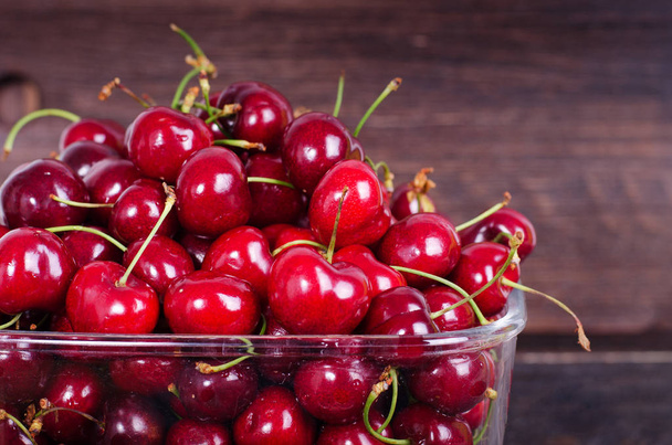 Sweet red cherries in glass bowl on dark wooden backgound with copy space. Summer and harvest concept. Vegan, vegetarian, raw food - Photo, Image