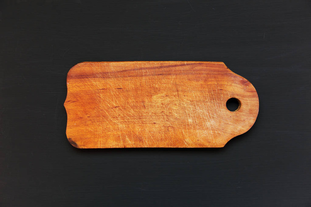 Old cutting board on dark background, top view - Фото, изображение