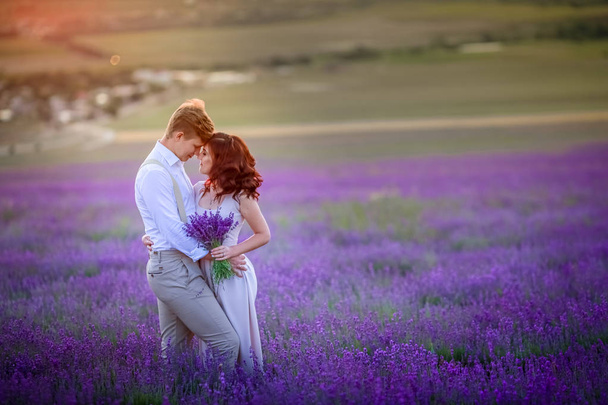 young couple in love posing at sunset on lavender field - Foto, Imagen