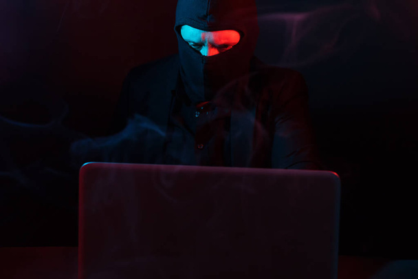Angry computer hacker in suit stealing data from laptop illumina - Valokuva, kuva